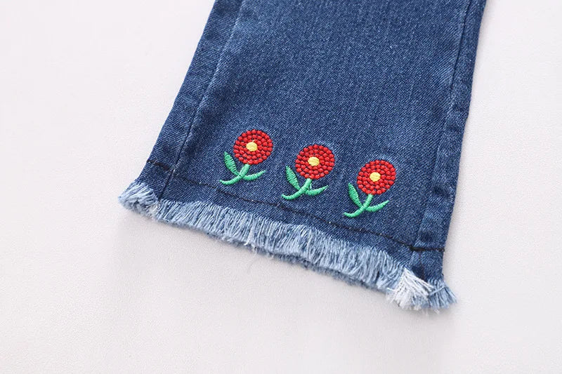 Close-up of floral details on girls' top and flare jeans 